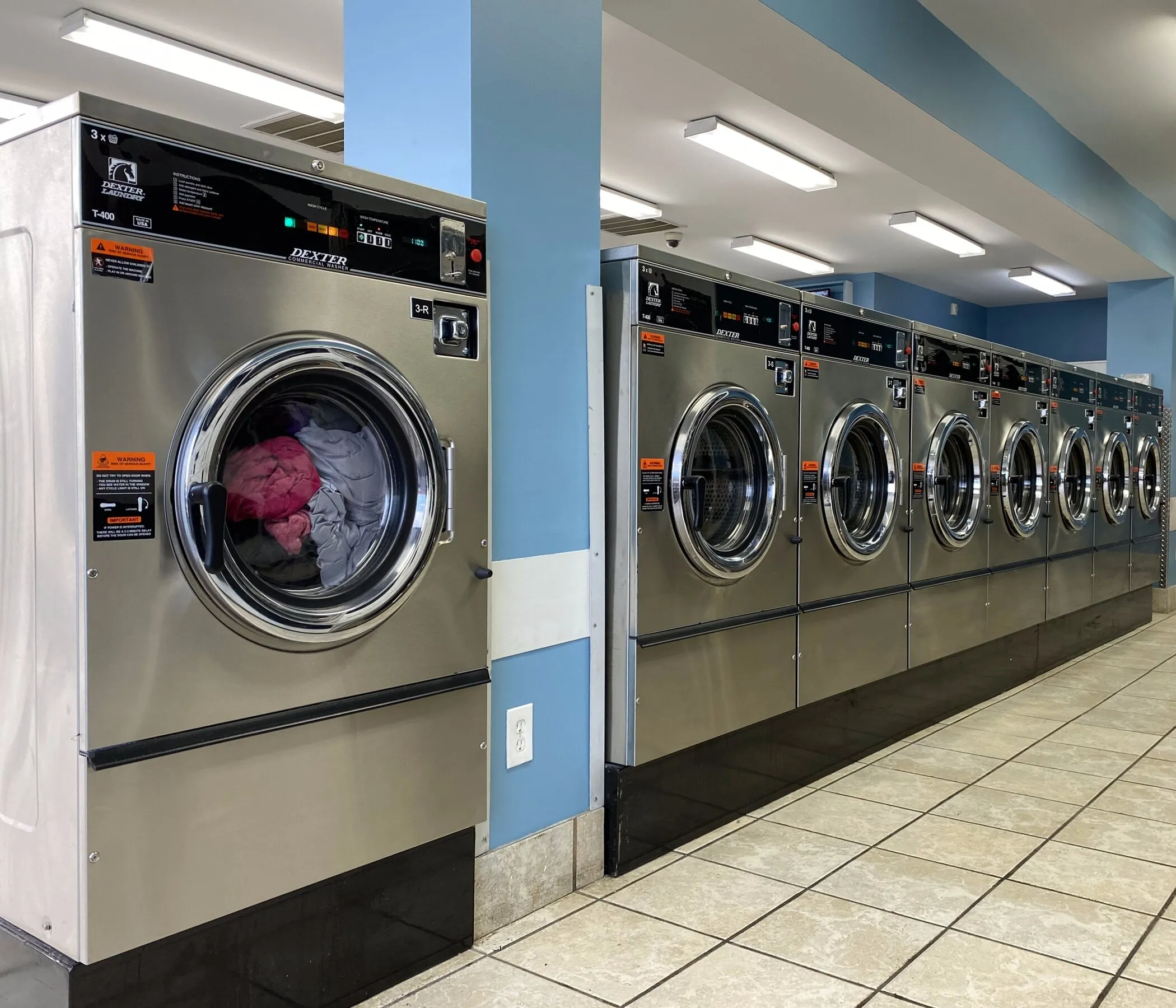 A row of large front-load washers, the nearest one loaded with laundry.