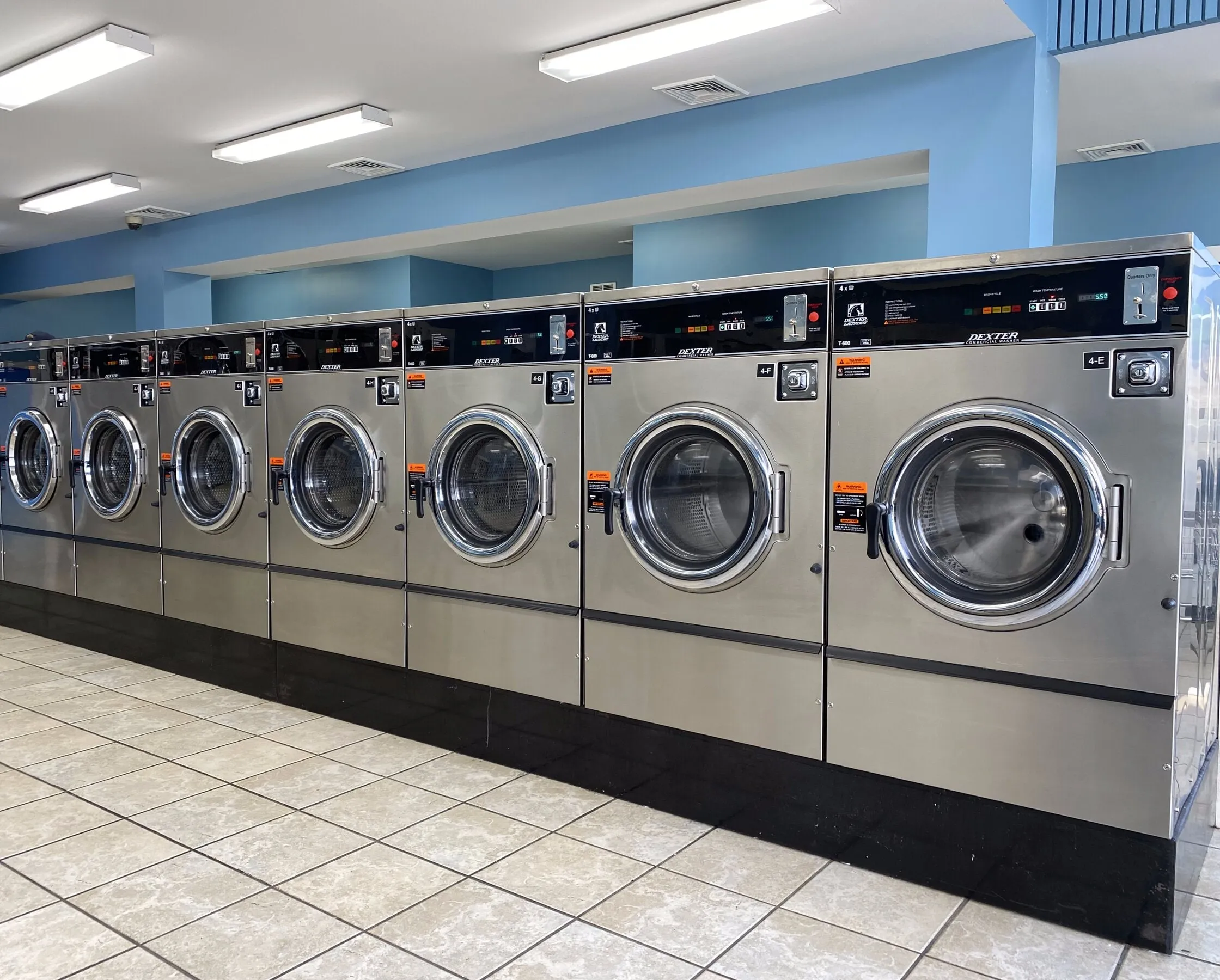 Large front-load washers in a row on a clean tile floor.