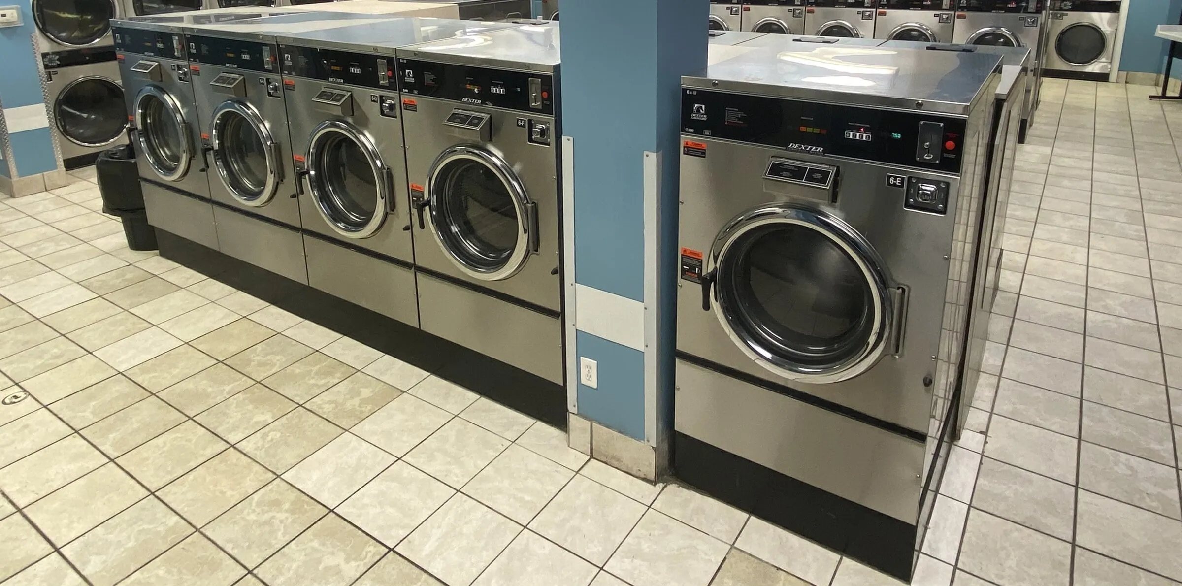 A washer island with a folding counter on top and dryers in the background.