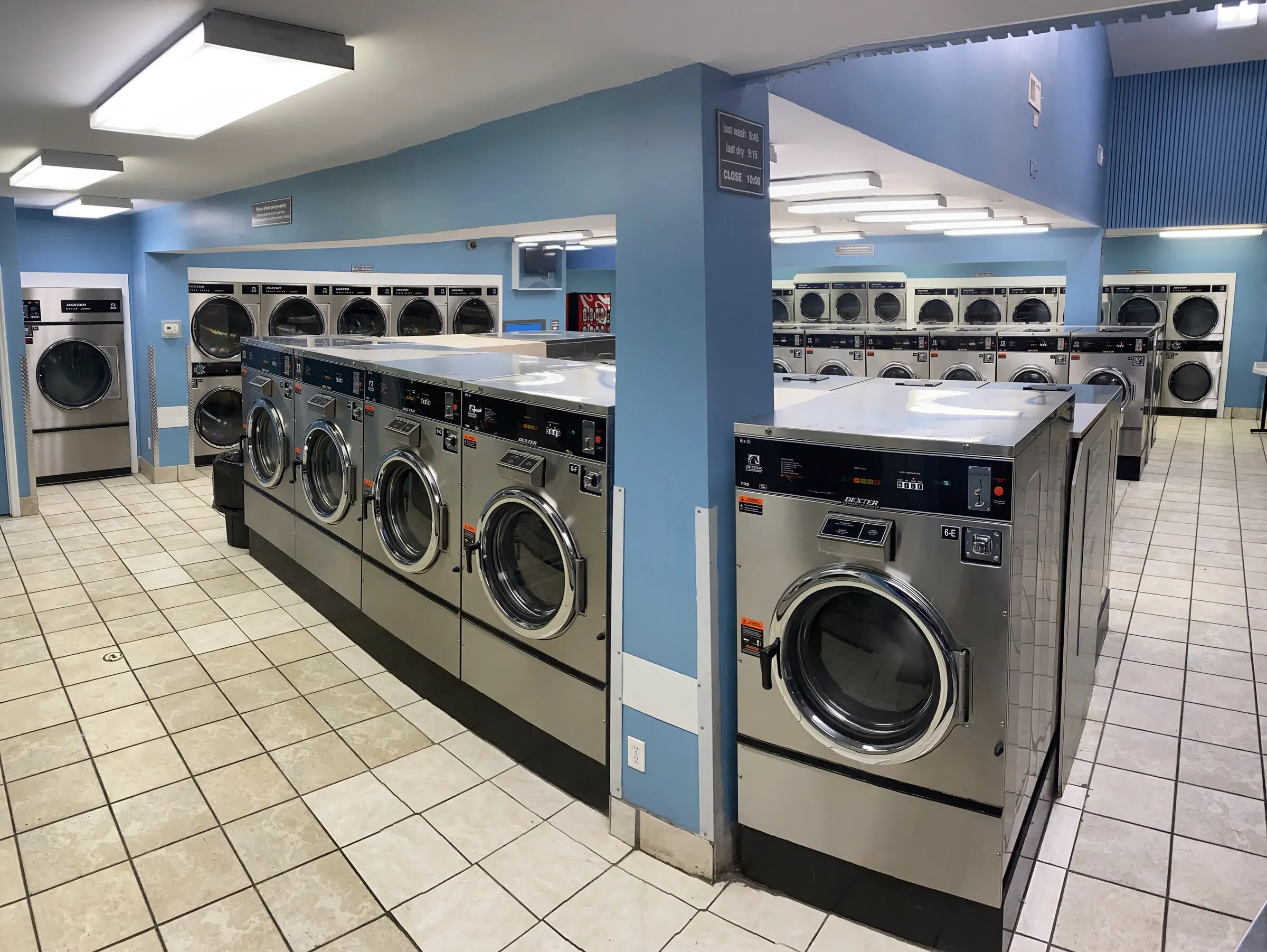 The laundromat floor looking toward the back, dryers along both sides.